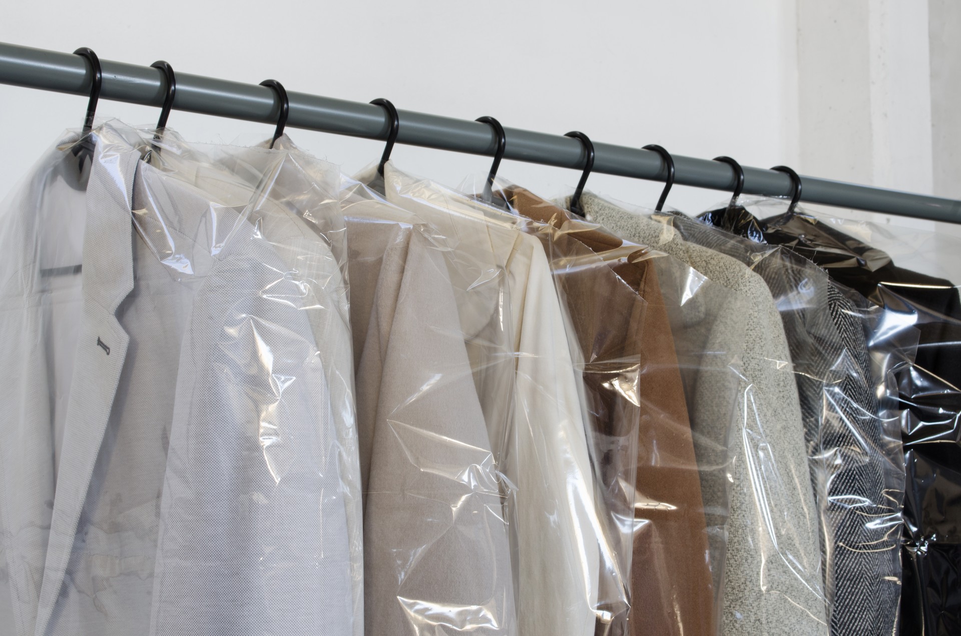 Rack with clean coats after dry cleaning on a dry cleaner. Quality laundry service. Hangers row. Winter season.