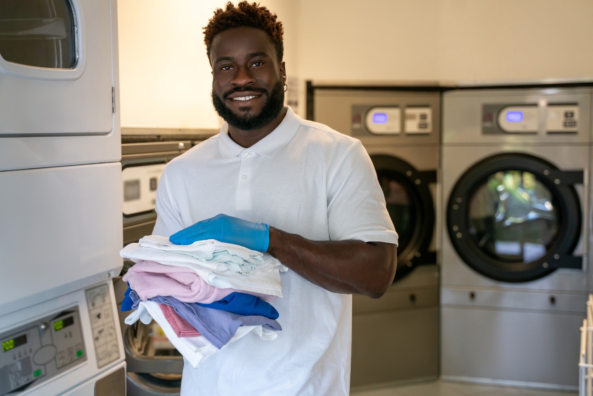 Contented guy standing among washing machines in a laundry facility